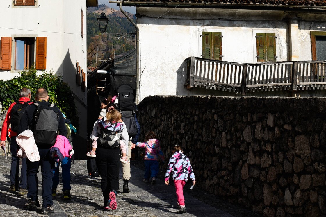 Passeggiate animate a Paluzza Famiglie con bambini che camminano tra i vicoli in pietra di Sutrio